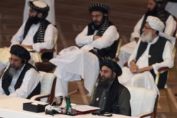 FILE - Taliban co-founder Mullah Abdul Ghani Baradar, bottom right, speaks at the opening session of the peace talks between the Afghan government and the Taliban in Doha, Qatar, Sept. 12, 2020.