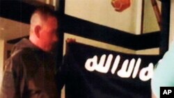 FILE - In this July 8, 2017 file image taken from FBI video and provided by the U.S. Attorney's Office in Hawaii on July 13, 2017, Army Sgt. 1st Class Ikaika Kang holds an Islamic State group flag after allegedly pledging allegiance to the terror group at a house in Honolulu. 