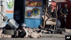 National police take cover as gunshots ring out at the end of a ceremony marking the 212th anniversary of the assassination of independence hero Gen. Jean-Jacques Dessalines in Port-au-Prince, Haiti, Oct. 17, 2018. 