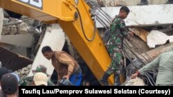 Petugas mengevakuasi korban yang terjebak di bawah reruntuhan kantor Gubernur Sulawesi Barat di Mamuju, Jumat, 15 Januari 2021. (Foto: Courtesy/Taufiq Lau/Pemprov Sulawesi Selatan)