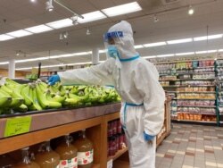 FILE - A shopper wearing a personal protective suit, mask and face shield shops for bananas at a Whole Foods Market during the outbreak of the coronavirus disease, in Pasadena, California, Jan. 20, 2021.