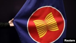 A worker adjusts an ASEAN flag at a meeting hall in Kuala Lumpur, Malaysia, October 28, 2021. REUTERS/Lim Huey Teng