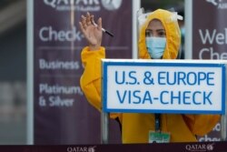 Una trabajadora de Qatar Airways, usando traje de protección contra el coronavirus, llama a pasajeros a chequearse en el aeropuerto internacional de Ninoy Aquino en Ciudad Pasay, Metro Manila, Filipinas.