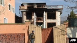 An Afghan policeman keeps watch at the gate of a foreign compound following an attack by Taliban militants in Kabul, Nov. 30, 2014. 