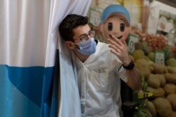 FILE - A medical professional with Clalit Health Services waves in his next patient to receive a coronavirus vaccine booster shot, at the Cinema City complex in Jerusalem, Aug. 30, 2021.