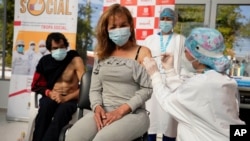 Un trabajador de la salud vacuna a una mujer sin hogar en un albergue municipal para personas que viven en la calle en Bogotá, Colombia, el viernes 2 de julio de 2021.