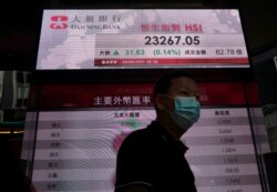 A man wearing face mask walks past a bank's electronic board showing the Hong Kong share index at Hong Kong Stock Exchange, Sept. 28, 2020.