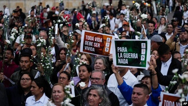 Viudas reclaman por asesinatos de más de 400 exguerrilleros de las FARC que pactaron la paz en Colombia 1 La gente sostiene flores y carteles durante un evento para recordar a los exguerrilleros y líderes sociales que han sido asesinados desde la firma de un acuerdo de paz en 2016 entre los rebeldes de las FARC y el gobierno, en Bogotá, Colombia, el martes 20 de febrero de 2024.