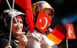 A Turkish woman waves a Turkish and a German flag during a demonstration including members of the Turkish ultra-nationalist organization called the Grey Wolves in Duesseldorf, western Germany, May 8, 2016.