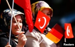 A Turkish woman waves a Turkish and a German flag during a demonstration including members of the Turkish ultra-nationalist organization called the Grey Wolves in Duesseldorf, western Germany, May 8, 2016.
