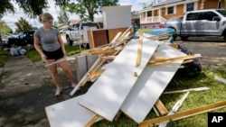 Kelsie Schmidt adds to a debris pile from her family's home after floodwater from Hurricane Francine came up a few inches in the house, in Kenner, Louisiana, Sept. 12, 2024.