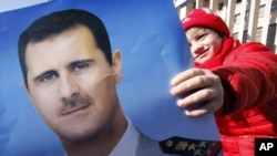 A pro-Syrian regime protester holds a portrait of Syrian President Bashar Assad during a demonstration to show support for their president, in Damascus, Syria. (File)