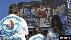 Admiradores de La Diva de la Banda observan en una pantalla los funerales de la cantante.