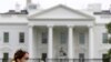 FILE - A woman wearing a face mask walks past the White House in Washington, April 1, 2020.