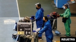 Pria yang mengenakan pakaian pelindung berjalan di halte bus di bandara internasional Narita pada hari pertama penutupan perbatasan untuk mencegah penyebaran varian virus corona baru omicron di Narita. (Foto: Reuters)