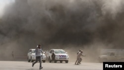 People react as dust rises after explosions hit Aden airport, upon the arrival of the newly-formed Yemeni government in Aden, Yemen, Dec. 30, 2020. 