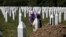 FILE - A woman touches the tombstone of a relative at the Potocari, memorial complex near Srebrenica, 150 kilometers northeast of Sarajevo, Bosnia, July 10, 2015. 
