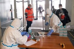 Health department employees in protective clothes measure the body temperature of around 160 Romanian seasonal workers after landing at Hahn Airport in Hahn, Germany, April 13, 2020.