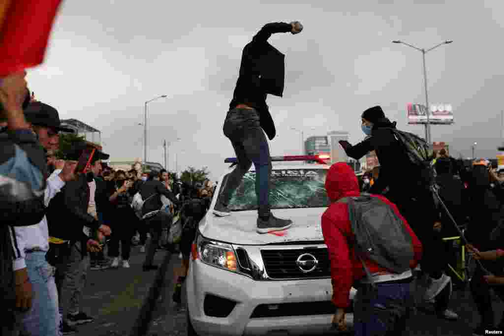 Manifestantes han destruido carros de polic&#237;a, como en esta imagen donde un hombre se prepara para tirar una piedra a un veh&#237;culo policial.