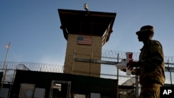 In this June 5, 2018 photo, reviewed by U.S. military officials, a task force member walks past the Camp 6 detention facility at the Guantanamo Bay U.S. Naval Base, Cuba. 