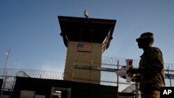 FILE - A task force member walks past the Camp 6 detention facility at the Guantanamo Bay U.S. Naval Base, Cuba, in this June 5, 2018 photo, reviewed by U.S. military officials. 