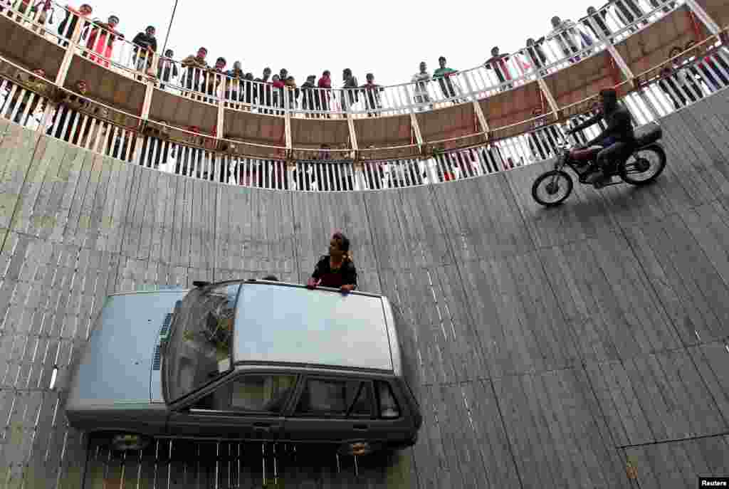 Stunt performers ride a motorcycle and a car on the walls of the &quot;Well of Death&quot; at the Magh Mela fair in Allahabad, India.