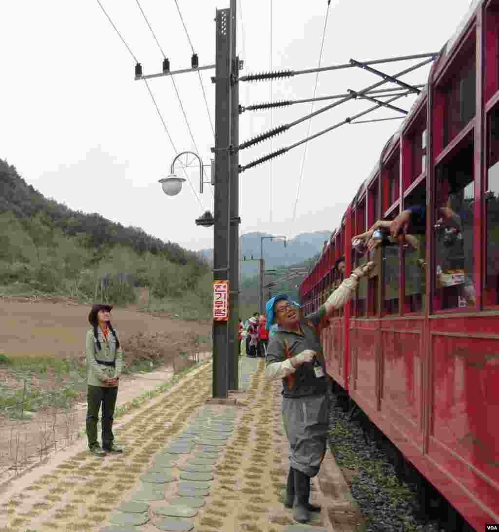 Seorang petani menukar telur dengan bir dari penumpang Kereta-V dalam salah satu pemberhentian singkat di sebuah stasiun pedesaan (9/5). (VOA/R. Kalden)