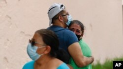 People embrace on the street as they wait for the all-clear to return to their apartment after an earthquake in Mexico City, June 23, 2020. 