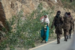 In this Friday, May 7, 2021 file photo, a woman walks past Ethiopian government soldiers by the side of a road north of Mekele, in the Tigray region of northern Ethiopia.