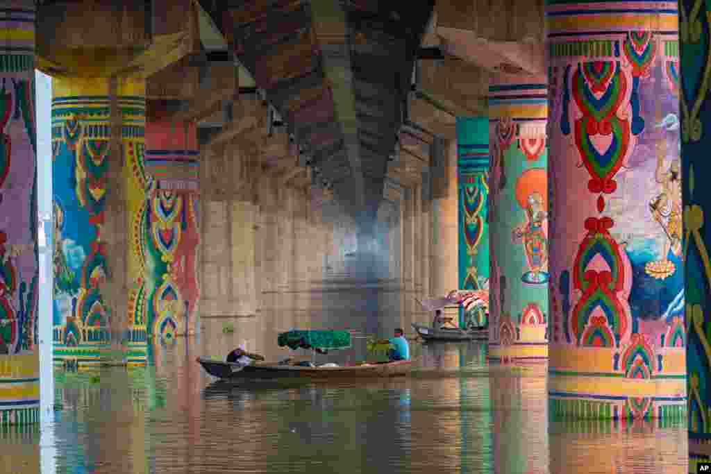 People row their boats on the swollen Ganges River in Prayagraj, India.
