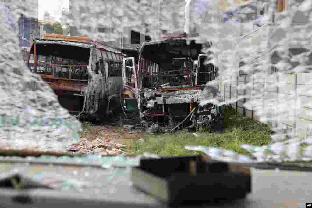 Charred remains of passenger buses owned by a transport company from the neighboring Tamil Nadu state, are seen through the shattered glass of another bus vandalized by angry mobs in Bangalore, capital of the southern Indian state of Karnataka. Authorities imposed a curfew amid widespread protests overnight over the country&#39;s top court ordering the southern state of Karnataka to release water from a disputed river to the neighboring state.