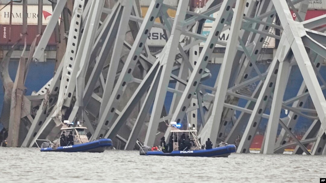 Kapal milik polisi bergerak di dekat kapal kargo yang terjebak di struktur jembatan Francis Scott Key di Baltimore, Maryland, pada 27 Maret 2024. (Foto: AP/Steve Helber)