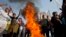 Pakistani Christians chant slogans after they burn a tire during a demonstration demanding that the government rebuild their homes after they were burned down following an alleged blasphemy incident, in Islamabad, Pakistan, March 10, 2013.