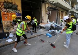 Volunteers clean debris from the street following Tuesday's blast in Beirut's port area, Lebanon, Aug. 7, 2020.