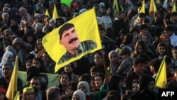 A Syrian Kurdish woman waves a flag bearing a picture of the founder of the Kurdistan Workers' Party Abdullah Ocalan, as people gather in the Kurdish-majority city of Qamishli in northeastern Syria to listen to a message from the jailed leader, Feb. 27, 2025. 