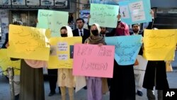 FILE - Afghan university students chant slogans and hold placards during a protest against the ban on university education for women, in Quetta, Pakistan, Dec. 24, 2022.