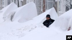 Un hombre trata de abrirse paso en busca de su auto entre la nieve a la puerta de su casa en Boston, luego de la severa nevada que entre viernes y sábado azotó el noreste de EE.UU.