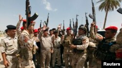 Les membres des forces de sécurité irakiennes scandent des slogans à Bagdad le 13 Juin 2014., après que le président américain Barack Obama eut annoncé la possiblité de frappes militaires contre les insurgés