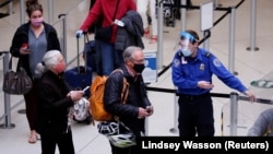 A TSA worker directs travelers to the next station at a security checkpoint at Seattle-Tacoma International Airport in SeaTac, Washington, U.S. April 12, 2021.