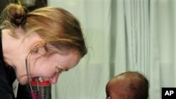 In this 21 Jan 2010 photo, Lt. Jerri Gram, from Huntsville, Ala., a doctor aboard the Military Sealift Command hospital ship USNS 'Comfort,' shares a smile with a female infant during an examination off the coast of Port-au-Prince, Haiti