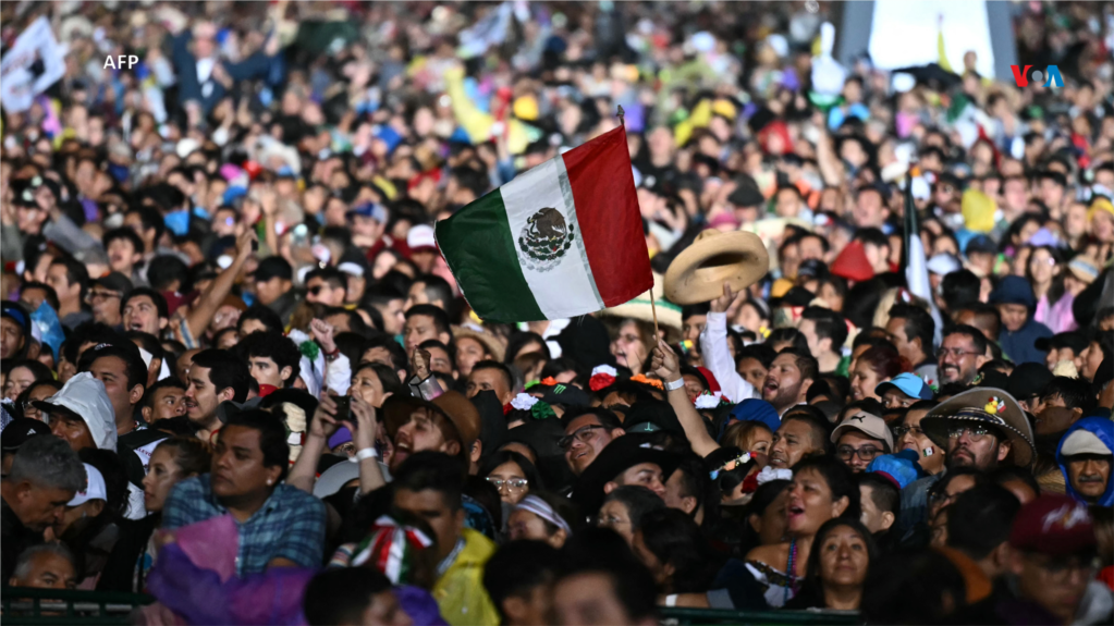 Un hombre sostiene una bandera mexicana, mientras la gente asiste a la ceremonia del &#39;Grito de Independencia&#39; que marca el inicio de las celebraciones del Día de la Independencia en la Plaza El Zócalo de la Ciudad de México.