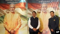 kepala pemerintahan negara bagian Maharashtra, Devendra Fadnavis (kiri) dan aktor Bollywood Vivek Oberoi berpose di depan poster film "PM Narendra Modi," di Mumbai, India, 7 Januari 2019. (Foto: dok).