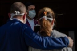 A priest and mourners wear face masks to guard against coronavirus infection at a funeral in Madrid, March 27, 2020.