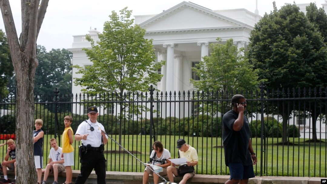 FILE - A Uniformed Division Secret Service police officer patrols with a dog as visitors walk on Pennsylvania Avenue in front of the White House in Washington, July 9, 2014.