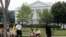 FILE - A Uniformed Division Secret Service police officer patrols with a dog as visitors walk on Pennsylvania Avenue in front of the White House in Washington, July 9, 2014.
