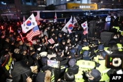 Police officers stand guard as pro-Yoon supporters, back, try to enter the compound of the Seoul Western District Court in Seoul on Jan. 18, 2025.