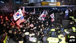 Police officers stand guard as pro-Yoon supporters, back, try to enter the compound of the Seoul Western District Court in Seoul on Jan. 18, 2025, as the court weighs whether to extend the detention of impeached South Korea President Yoon Suk Yeol.