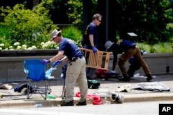 Members of the FBI's evidence response team remove personal belongings one day after a mass shooting in downtown Highland Park, Ill., Tuesday, July 5, 2022. A shooter fired on an Independence Day parade from a rooftop spraying the crowd with gunshots initially mistaken for fireworks before hundreds of panicked revelers of all ages fled in terror. (AP Photo/Charles Rex Arbogast)