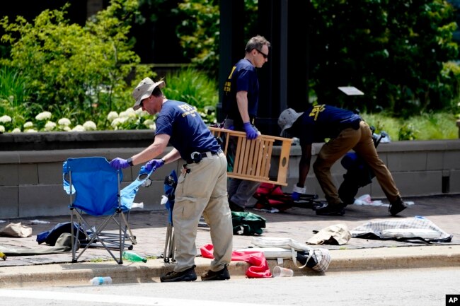 Members of the FBI's evidence response team remove personal belongings one day after a mass shooting in downtown Highland Park, Ill., Tuesday, July 5, 2022. A shooter fired on an Independence Day parade from a rooftop spraying the crowd with gunshots initially mistaken for fireworks before hundreds of panicked revelers of all ages fled in terror. (AP Photo/Charles Rex Arbogast)