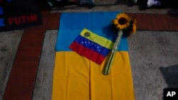 Una bandera de Venezuela y un girasol sobre una bandera Ucrania durante una protesta contra la invasión rusa, frente a las oficinas de la Unión Europea en Caracas, el 3 de marzo de 2022.
